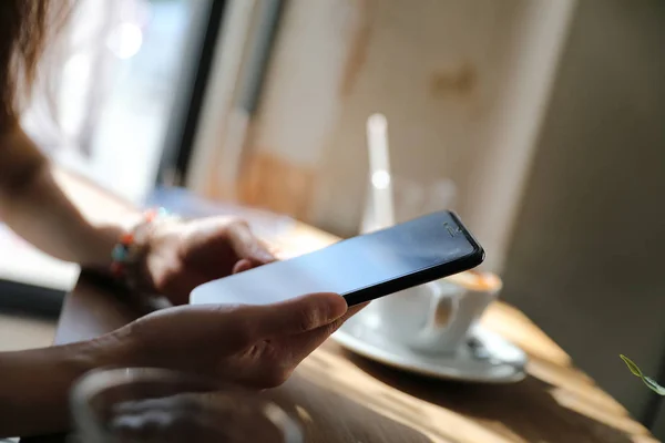 Woman hand shopping with phone on coffee shop