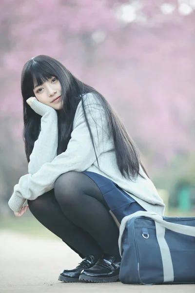 Japonés escuela chica vestido sentado con sakura flor naturaleza wal —  Fotos de Stock