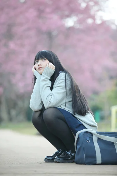 Japonés escuela chica vestido sentado con sakura flor naturaleza wal —  Fotos de Stock