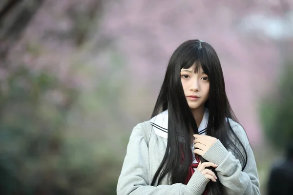 Escola japonesa menina vestido olhando sakura flor natureza passarela — Fotografia de Stock