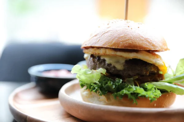 Hovězí hamburger se sýrově zeleným salátovým vejcem a omáčkou v restauraci — Stock fotografie