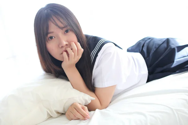 Портрет японской школьницы в комнате белого тона кровать — стоковое фото