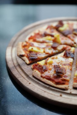 Hawaii pizzası, jambonlu pizza, ananas ve ahşap tabak.