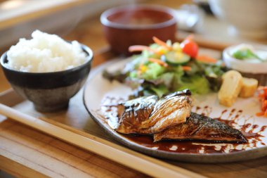 Saba balığı teriyaki, pirinç çorbası ve ahşap arka planda salata. ,