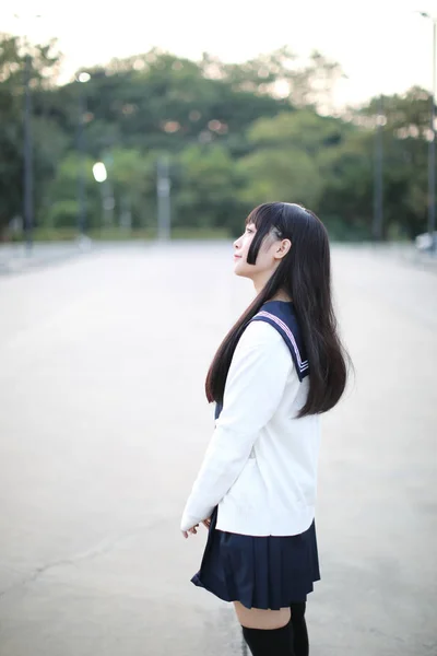 Aziatisch schoolmeisje wandelen in stedelijke stad met groene darden — Stockfoto