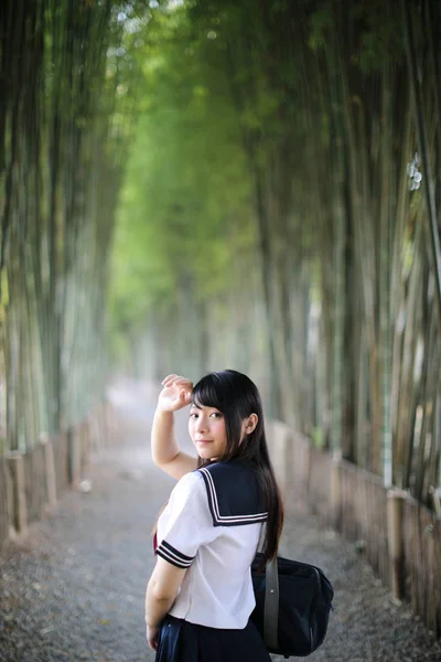 Ritratto di asiatico giapponese scuola ragazza costume cercando in bambù — Foto Stock