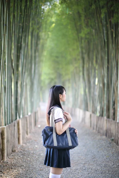 Ritratto di asiatico giapponese scuola ragazza costume cercando in bambù — Foto Stock