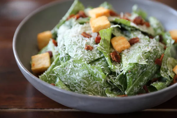 Caesar salad with crispy bread and bacon close up on wood backgr — Stock Photo, Image