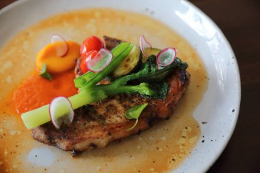 Izgara domuz pirzolası ve ahşap arka planda sebzeler.