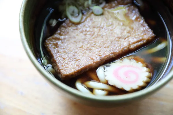 Kitsune udon nudlar med fisk boll och tofu på trä bakgrund — Stockfoto