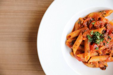Penne arrabiata makarna soslu baharatlı İtalyan yemeği ahşap arka planda.