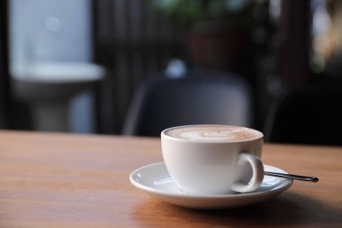 Kahve dükkanının ahşap masasındaki sütten yapılmış kapuçino ya da Latte sanat kahvesi.