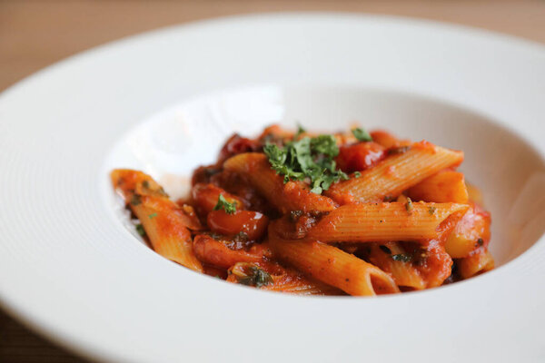 Penne arrabiata pasta tomato sauce with spices italian food on wood background