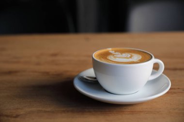 Kahve dükkanının ahşap masasındaki sütten yapılmış kapuçino ya da Latte sanat kahvesi.