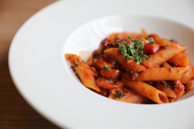 Penne arrabiata makarna soslu baharatlı İtalyan yemeği ahşap arka planda.