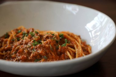 Parmesan peyniri ve fesleğenle süslenmiş kıyma ve domates soslu spagetti bolonez, İtalyan yemeği.