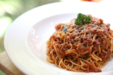 Parmesan peyniri ve fesleğenle süslenmiş kıyma ve domates soslu spagetti bolonez, İtalyan yemeği.