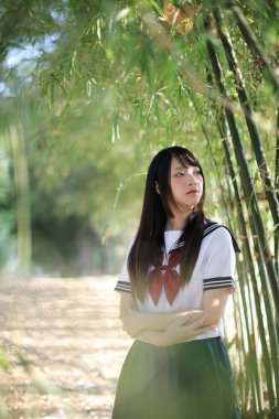 Bambu ormanlarında yaşayan güzel Asyalı liseli kız üniformasının portresi.