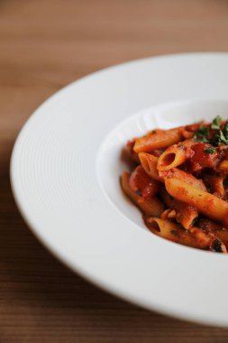 Penne arrabiata makarna soslu baharatlı İtalyan yemeği ahşap arka planda.