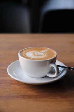 Kahve dükkanının ahşap masasındaki sütten yapılmış kapuçino ya da Latte sanat kahvesi.