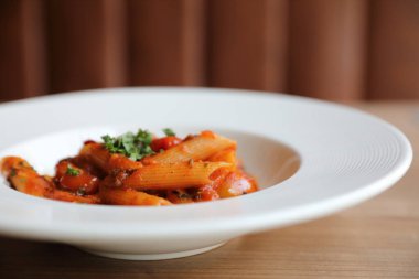Penne arrabiata makarna soslu baharatlı İtalyan yemeği ahşap arka planda.