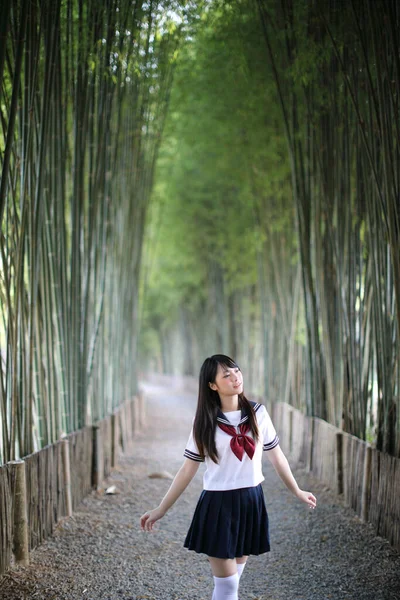美しいアジア系日本人女子高生の制服の肖像竹の森の背景 — ストック写真