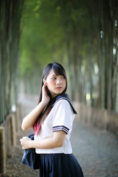 美しいアジア系日本人女子高生の制服の肖像竹の森の背景 — ストック写真