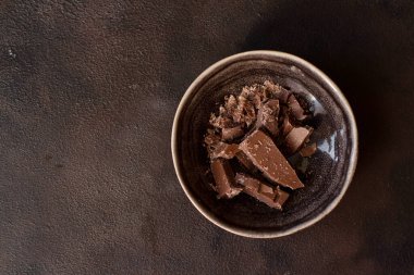 Kahverengi arka planda çikolata parçaları olan bir fincan..