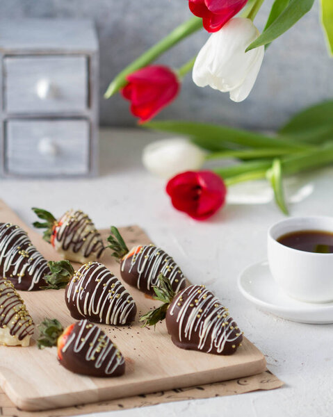 Клубника в шоколаде на доске на столе, с цветами
.