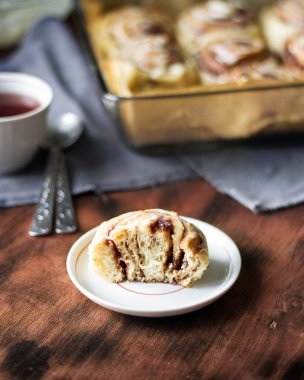 Sinnabbon çöreği ikiye bölünmüş ve tahta bir masada bir tabakta yatıyor.