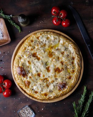 Etli ve baharatlı büyük yuvarlak turta, çekirdekler serpiştirilmiş, üst görünüm.