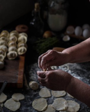 Kadın eli, arka planda hamur köftesi heykeli yapar.