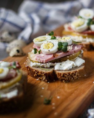 Bıldırcın yumurtalı sandviç, tahtadan yapılmış tahıl ekmeğinde et ve peynir.