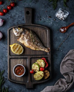 Öğle yemeği, ızgara sebzeler ve ahşap bir tahtanın üstünde sos..