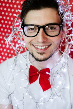 Genç hipster adam resmi giyim ve Noel ışıkları giyen bir yılbaşı partisinde 