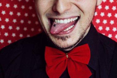 Genç hipster adam sopa ile bir piercing içinde onun dilini dışarı 