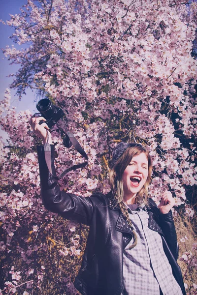 Vrouw met camera in de bloeiende bloemen — Stockfoto