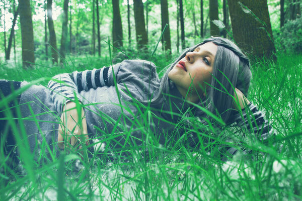 Portrait of Beautiful young woman in green grass at forest