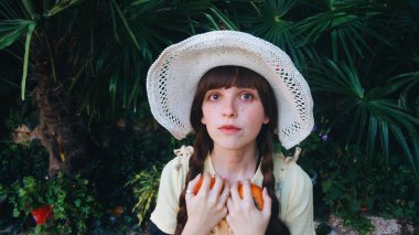 Young woman in hat holding persimmons 