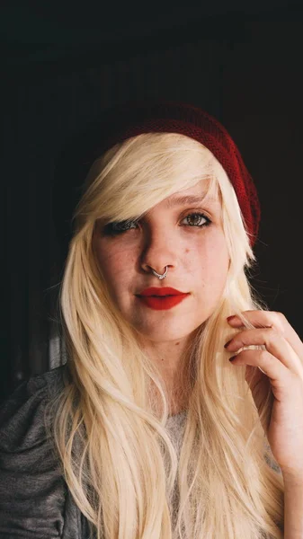 赤い唇と黒い背景にセーターに帽子と若いブロンドの女性の肖像画 — ストック写真