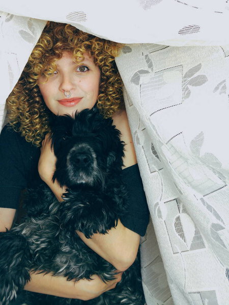 Портрет молодой женщины кудрявые с черной собакой на фоне