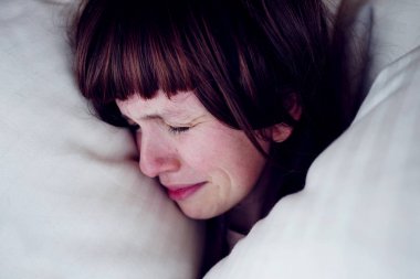 Yatakta kapalı gözler hüzünlü esmer Bayan portresi