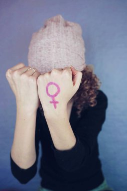 Yandan sembolünü gösterirken arka plan üzerinde pembe şapkalı kıvırcık saçlı sarışın genç kadın portresi