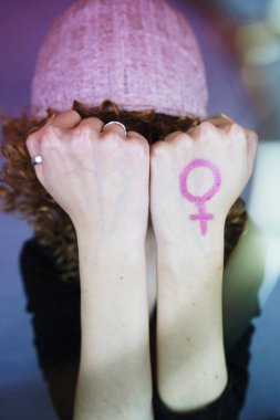 Pembe şapka kapak Eyes ile sarışın genç kadın portresi arka plan üzerinde eller