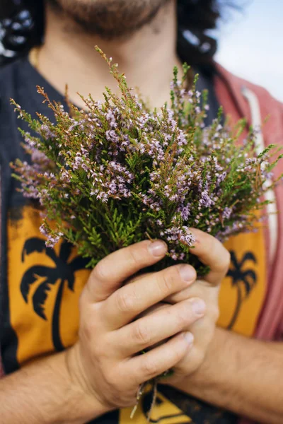 Las manos del hombre sosteniendo ramo de flores frescas de brezo — Foto de Stock