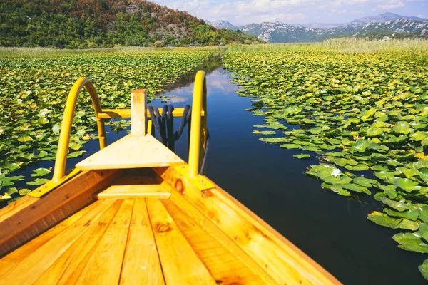 Viagem de lago entre lírios de água e montanhas em um barco de madeira (Ska — Fotografia de Stock