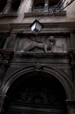 Gölge ile karanlık sokakta tarihi binada kanatları ile geleneksel Venedik sembolü aslan