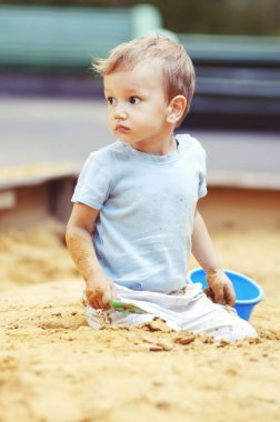 Kum havuzunda oynayan sevimli küçük çocuk