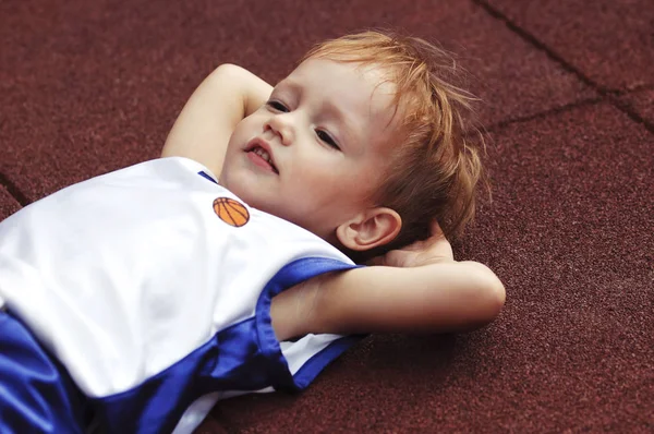 Rood haar schattige kleine jongen dragen een afte basketbal uniforme rust — Stockfoto