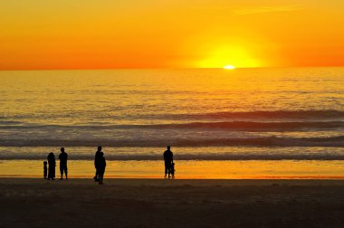Günbatımı Kaliforniya sahilde insanlar Silhouettes